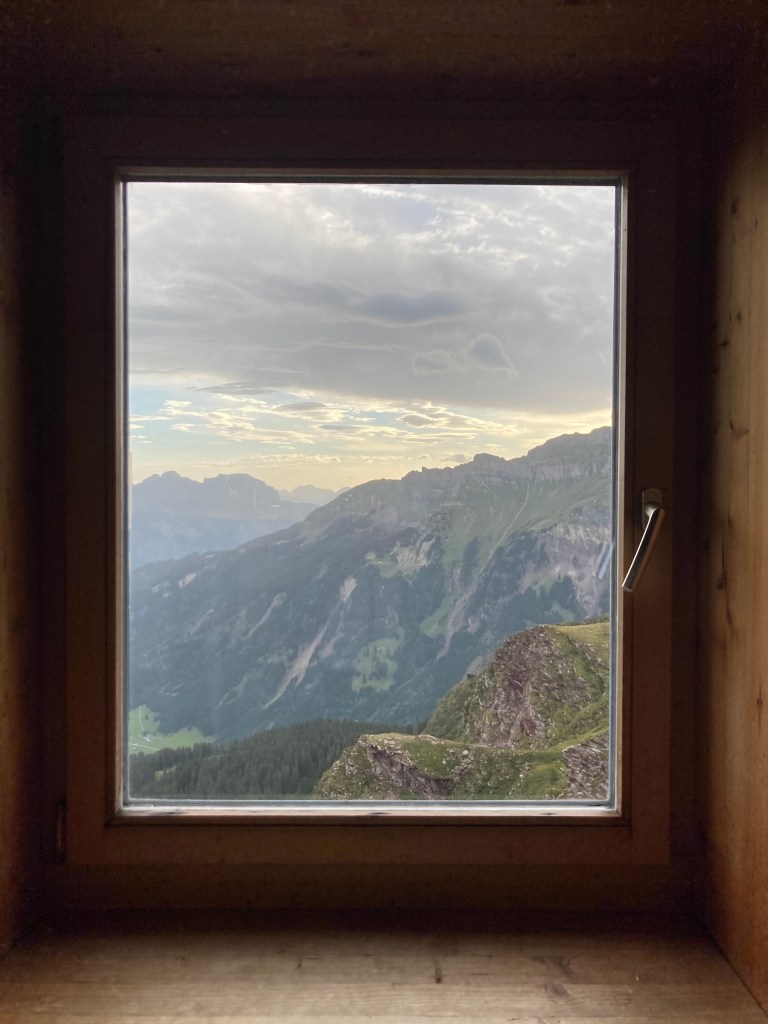 A window view from the Spitzmeilenhütte, Switzerland with a mountain landscape. Photo by Helena J. /Abroadland